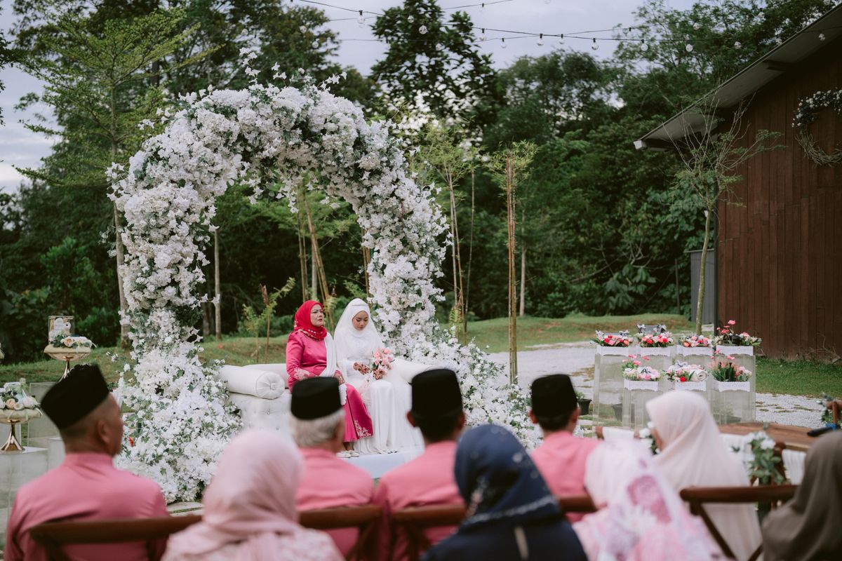 Editorial sample of an outdoor wedding ceremony beneath a floral arch